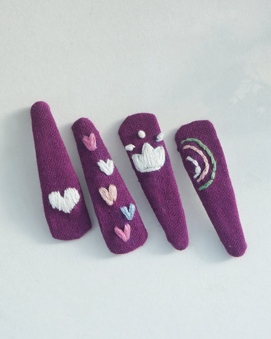 Purple finger puppets with heart and cloud designs on a light gray background